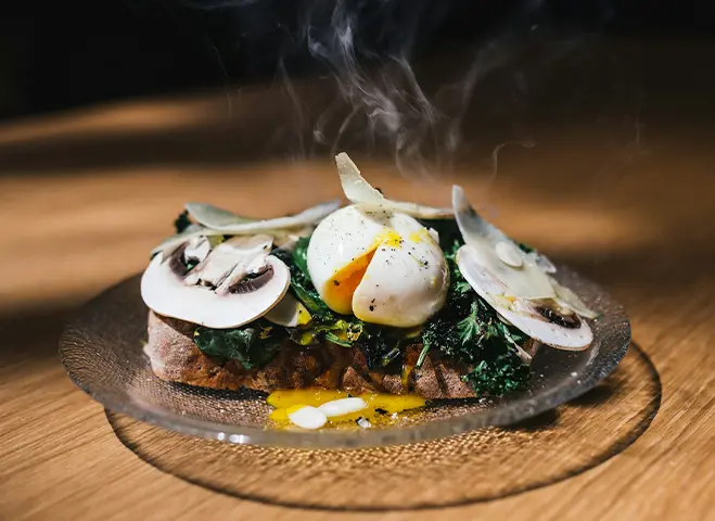 A freshly cooked plate of food, still steaming, with several mushroom slices on it